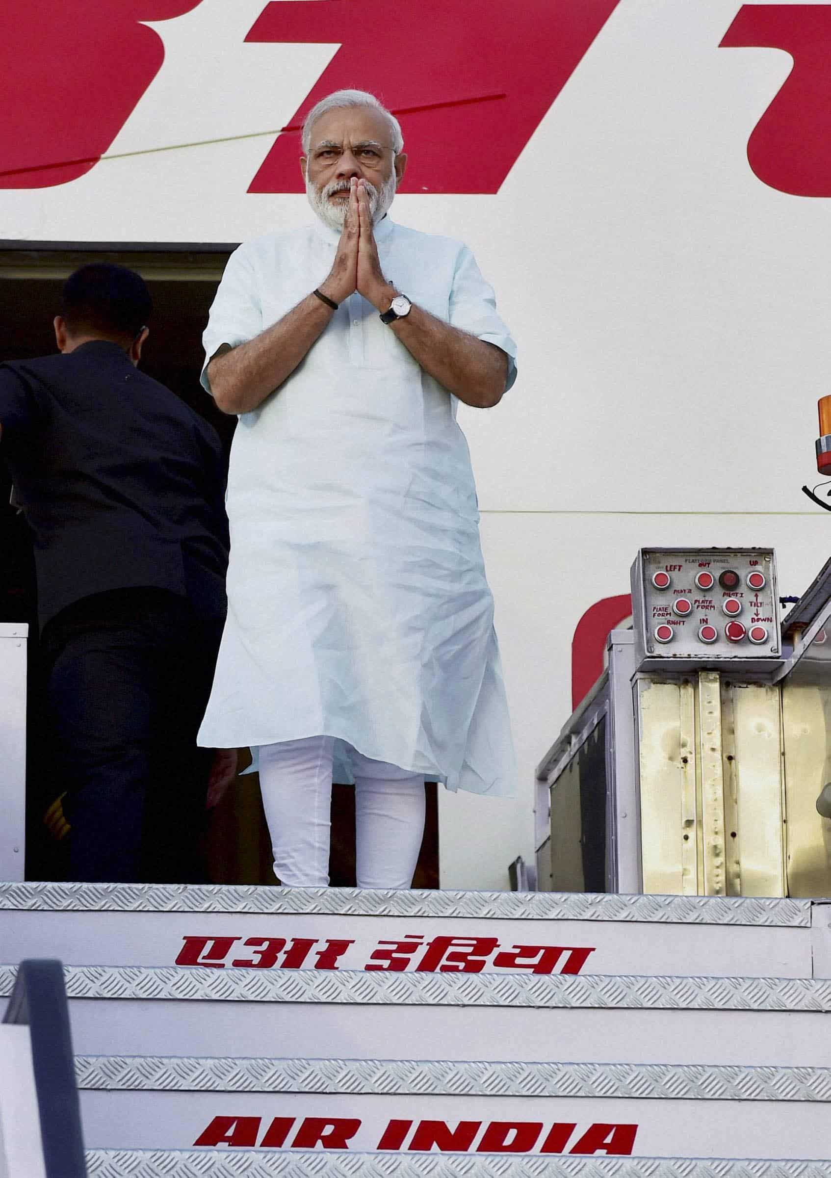 Prime Minister Narendra Modi gestures as he alights the stairs of the plane after returning from his five-nation tour at Air Force Station. PTI