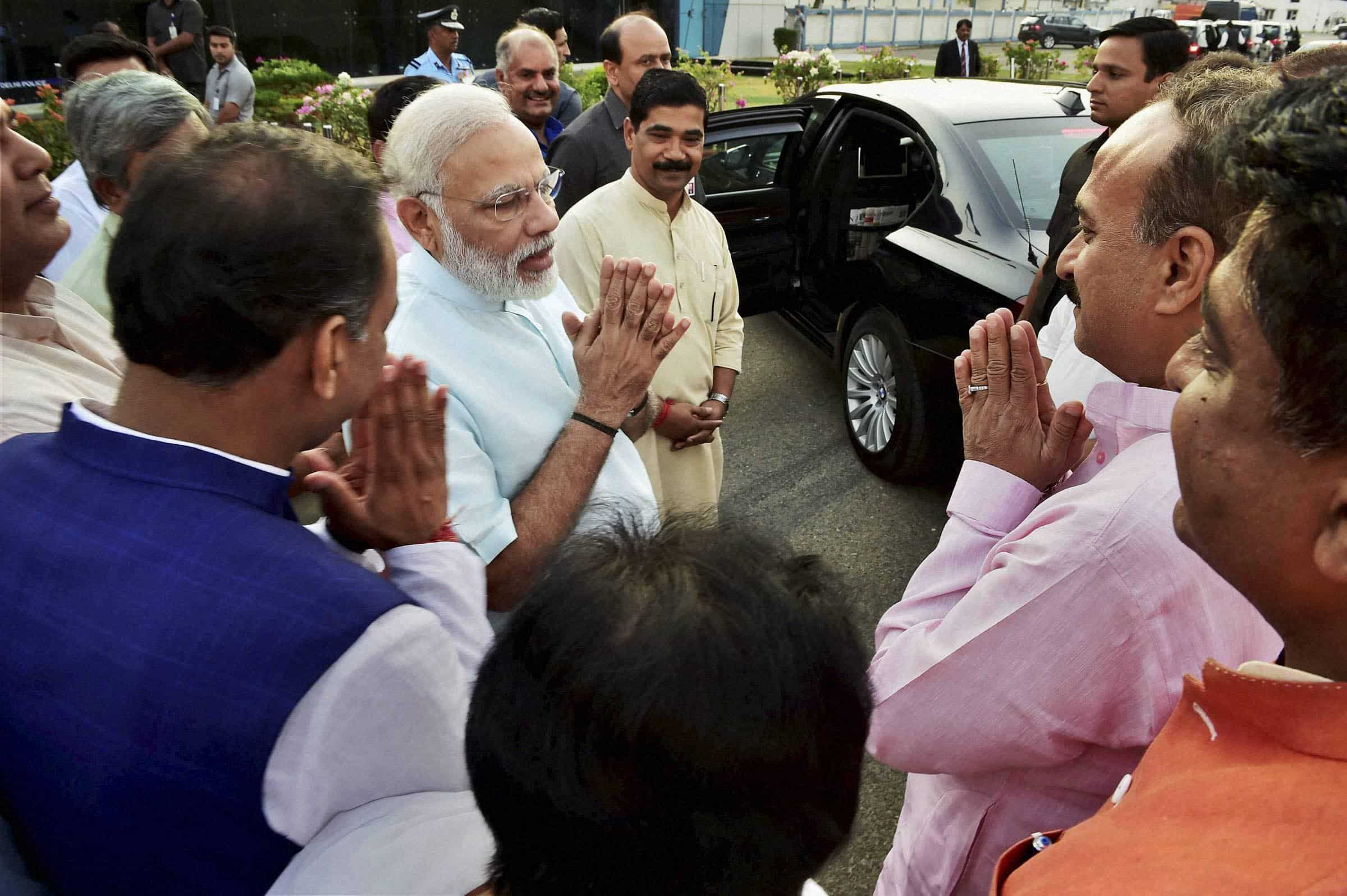 PM Narendra Modi exchanges greetings with BJP leaders on his arrival. PTI