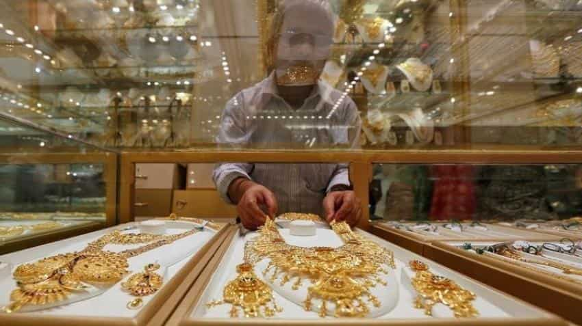 Gold holds gains on weaker dollar, rising stocks cap gains